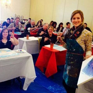 a paint & sip artist and customers at a paint & sip travel event