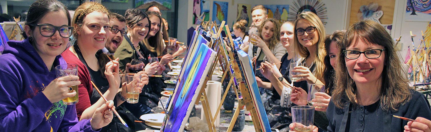 a group of people drinking beer and wine and painting at the Paint & Sip studio in Burlington, VT